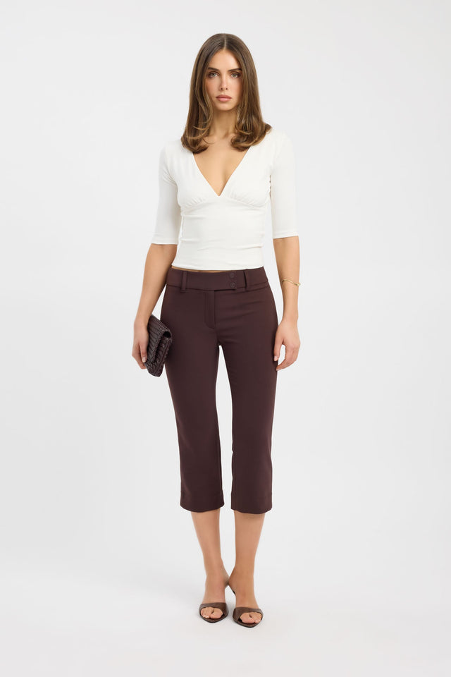 Woman wearing a white top and brown pants on a white background
